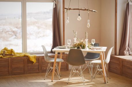 Et lyst og varmt rom med et bord som er dekket på med fire stoler plassert rundt seg og utsikt ut til et snødekket landskap gjennom vinduet